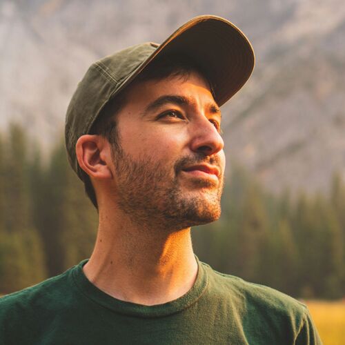 Man with cap with mountains and forest in the background